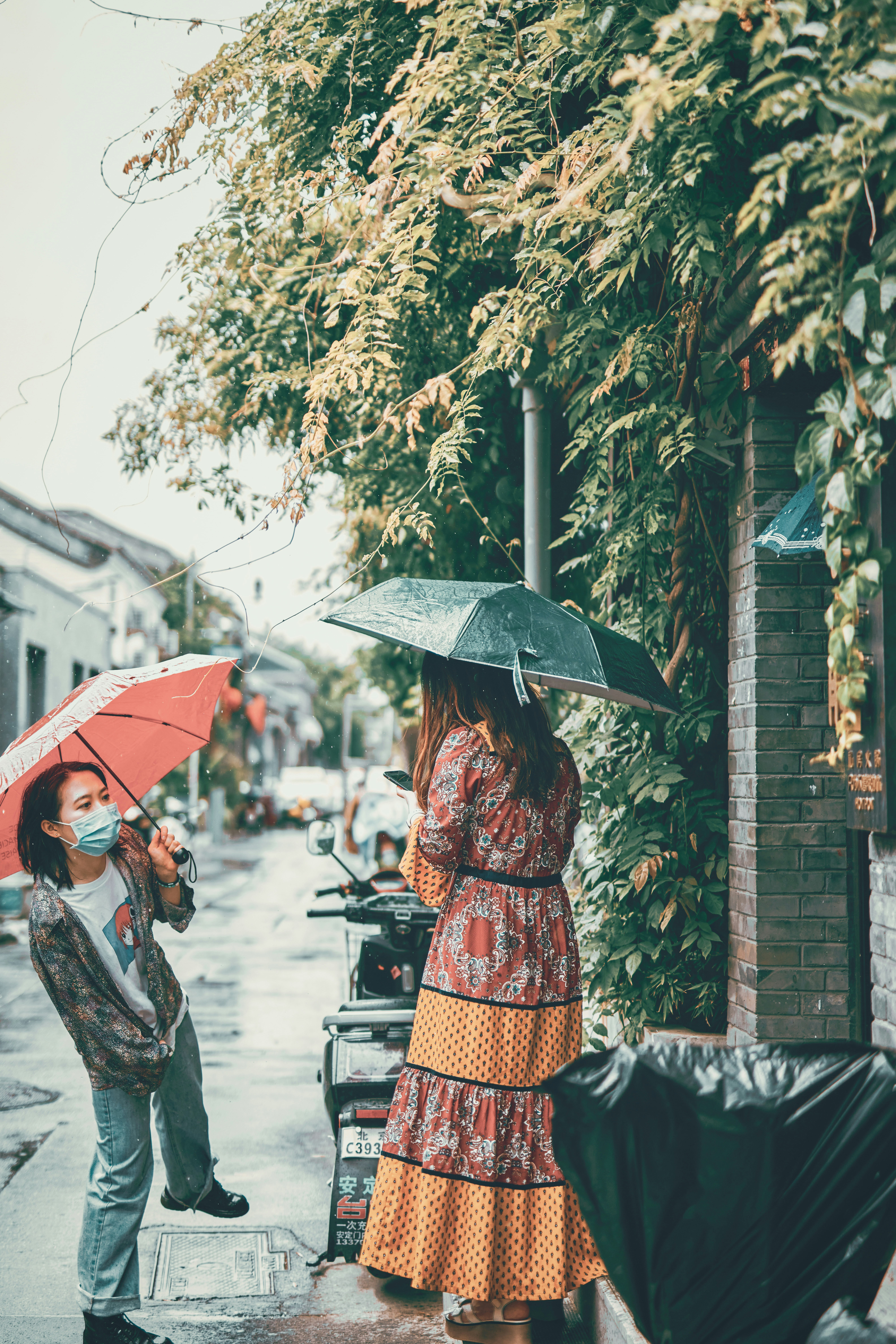 woman in red and brown dress holding umbrella walking on sidewalk during daytime