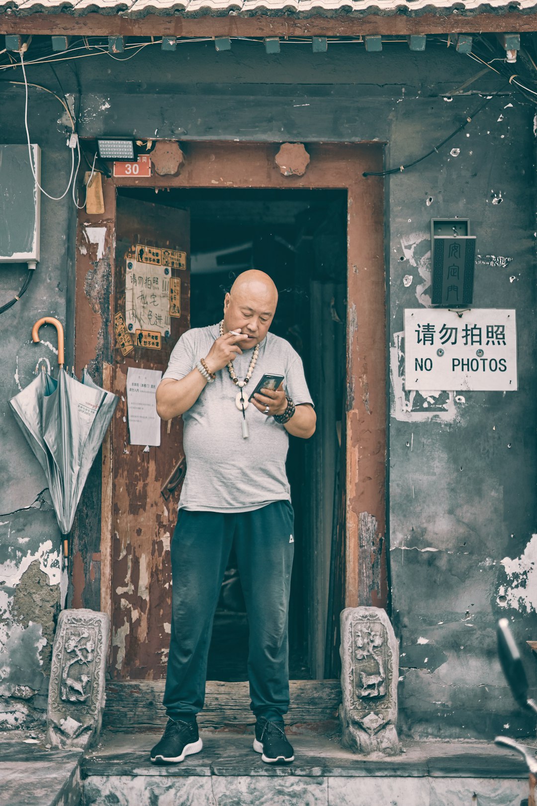 man in white crew neck t-shirt and blue denim jeans standing beside brown wooden door