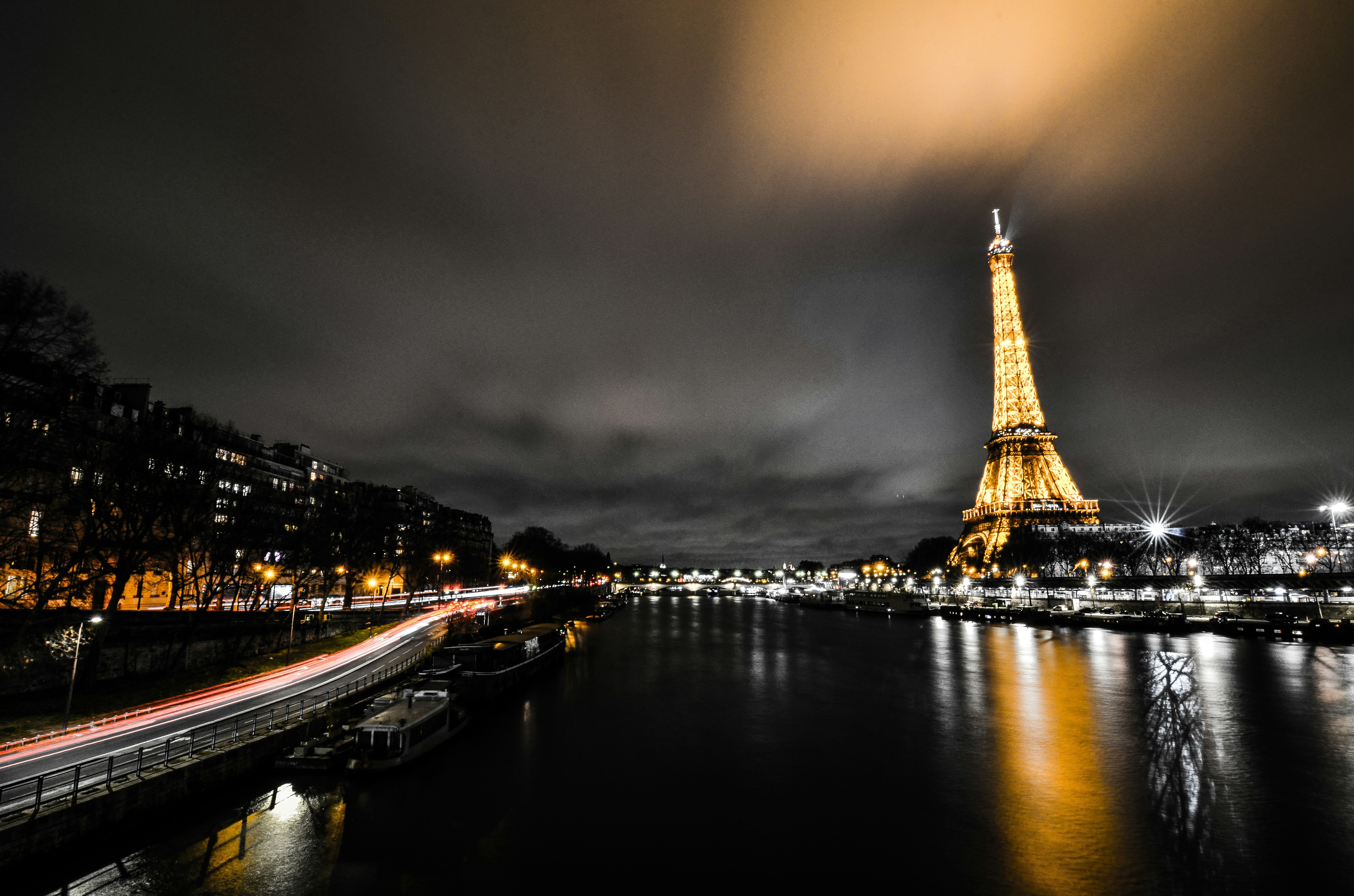 Paris Eiffel Tower illuminated at night with golden lights, Seine river reflection, romantic city atmosphere