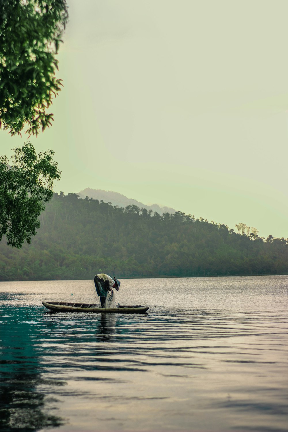 person sitting on brown wooden boat on body of water during daytime