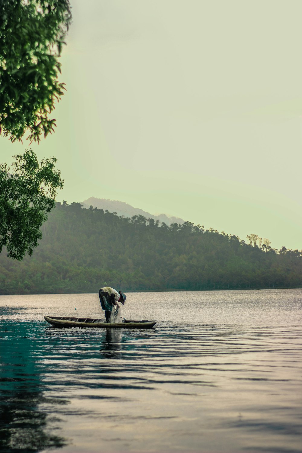 Person, die tagsüber auf einem braunen Holzboot auf einem Gewässer sitzt