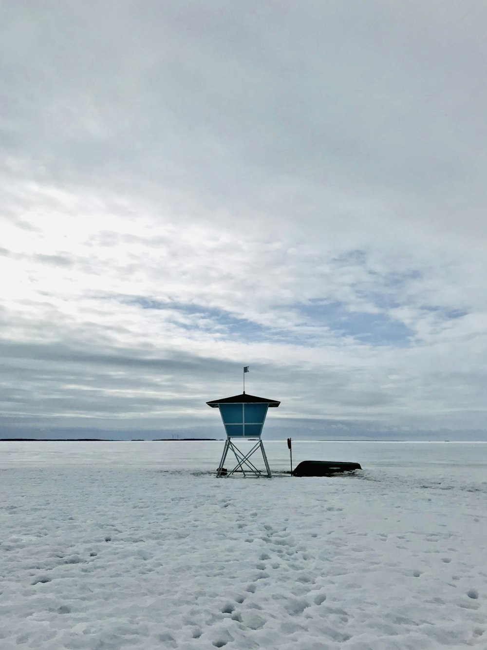 Weiß-schwarzes Rettungsschwimmerhaus am Strand unter bewölktem Himmel tagsüber