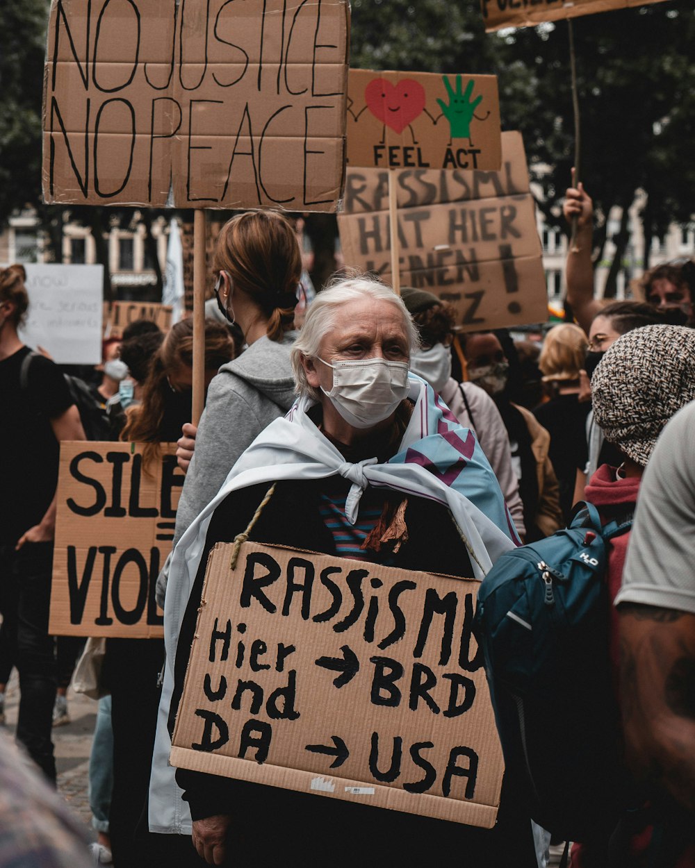 woman in blue shirt wearing white mask holding brown and black i am happy print tote