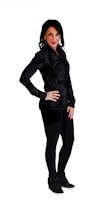 A person with dark hair is standing confidently, dressed in black attire against a plain white background. The person is wearing a zip-up jacket, leggings, and casual shoes, with one hand on their hip.