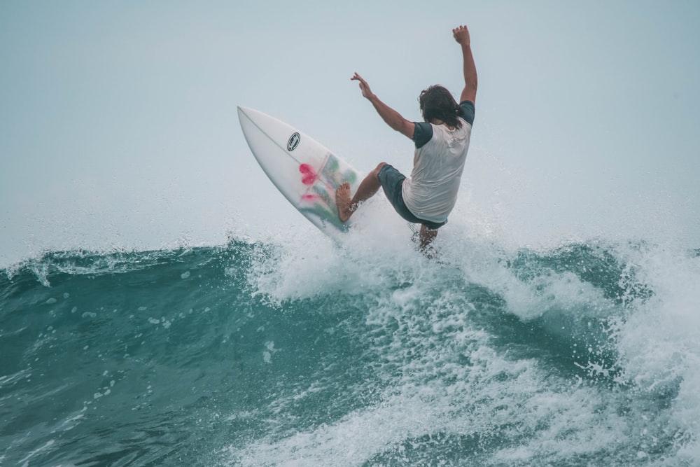 man in white t-shirt surfing on sea during daytime