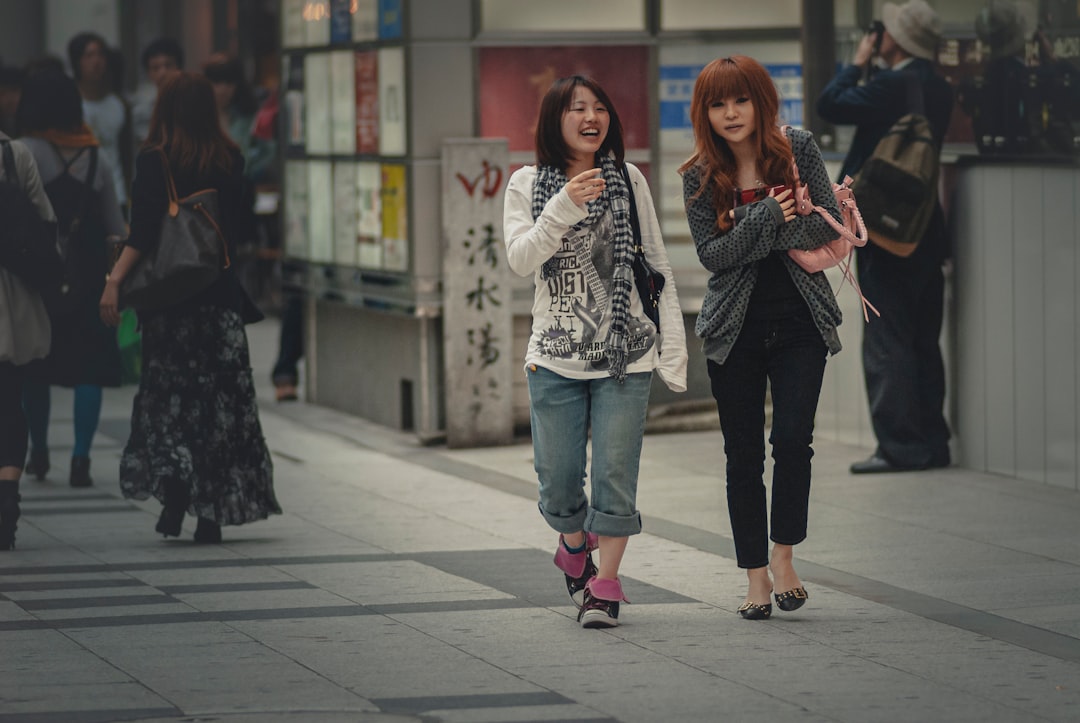 woman in white and black long sleeve shirt and blue denim jeans standing beside woman in with on with on