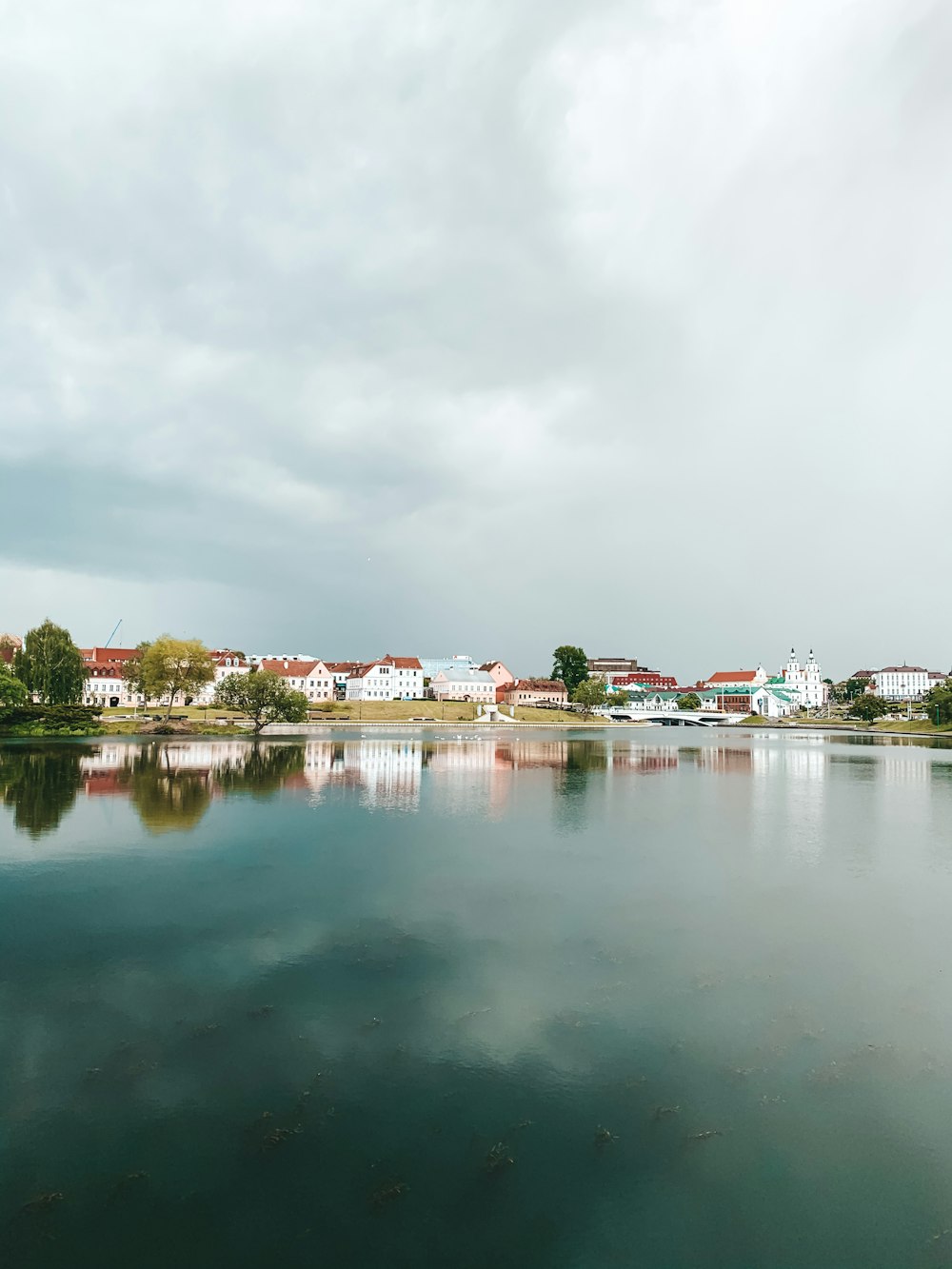 Maisons près d’un plan d’eau sous un ciel nuageux pendant la journée