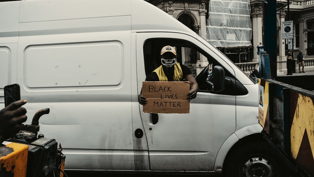 man in black and yellow jacket sitting on white van