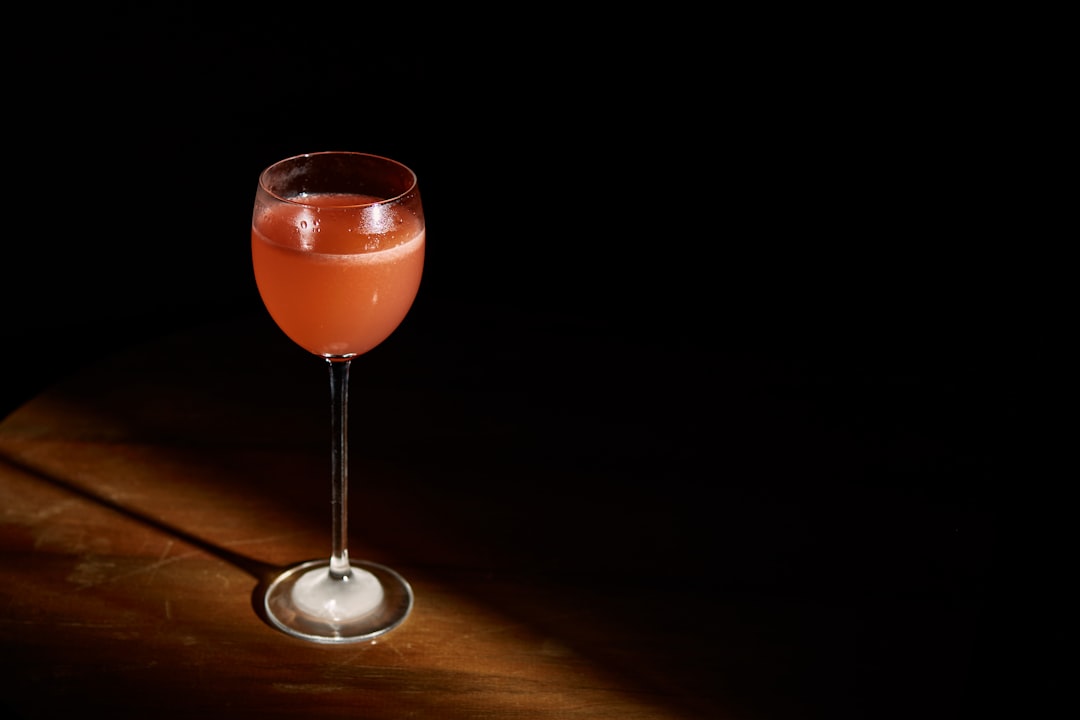 clear wine glass with red liquid, High Five Cocktail in the spot.