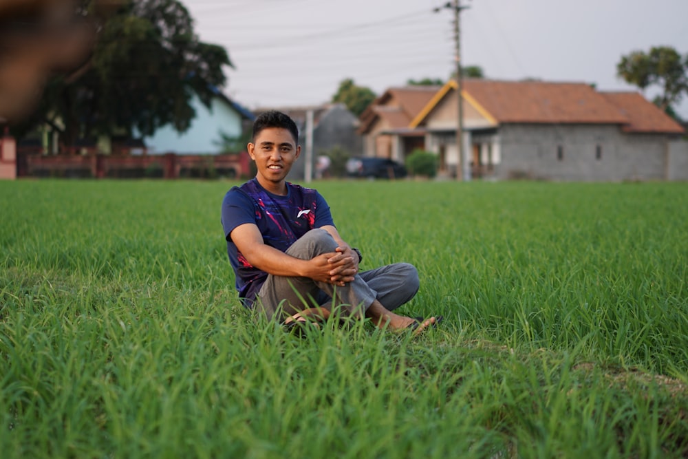 boy in blue crew neck t-shirt sitting on green grass field during daytime