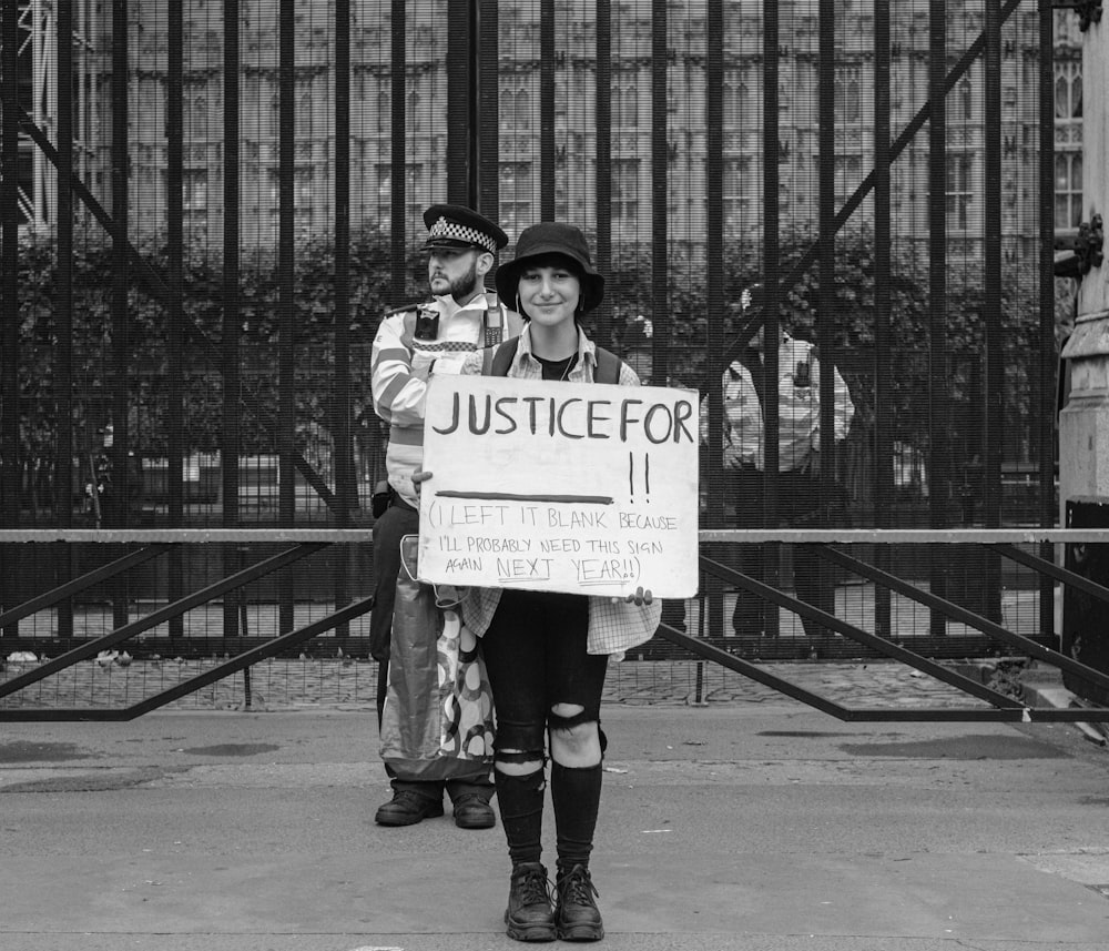 grayscale photo of woman holding white and black sign