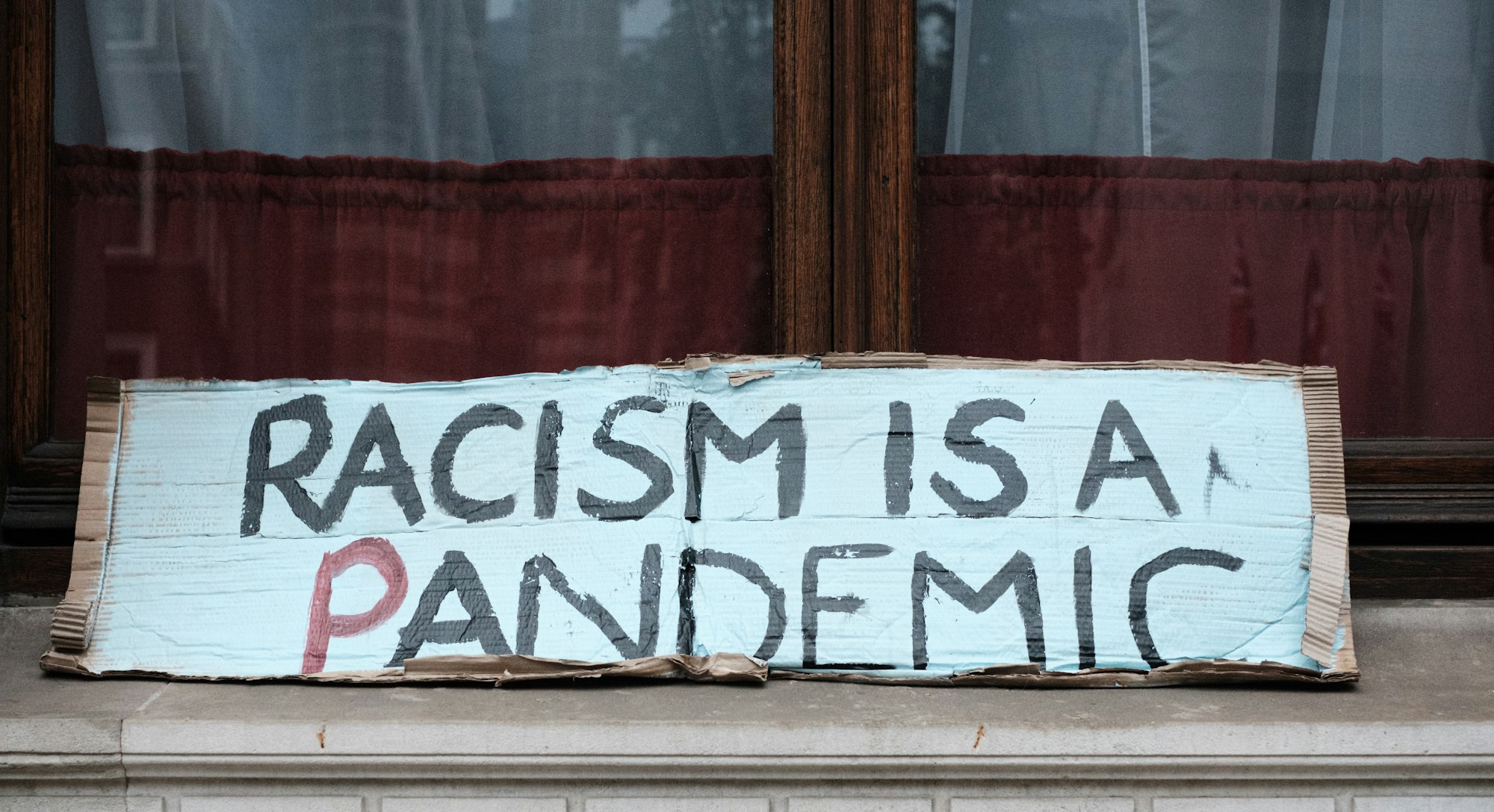 A sign propped on a doorstep reads "RACISM IS A PANDEMIC" at the London Black Lives Matter Peaceful Protest