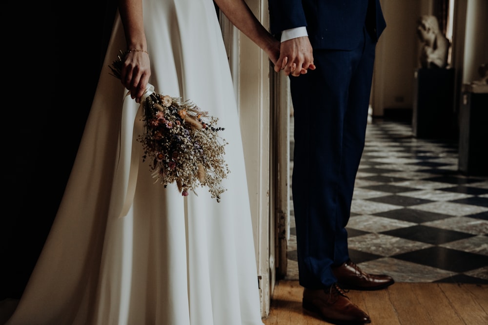 man in black suit holding woman in white dress