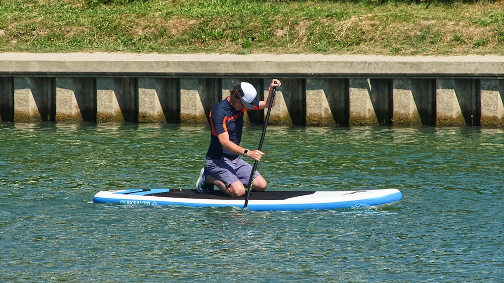 homme en chemise bleue et noire chevauchant un kayak bleu sur la rivière pendant la journée