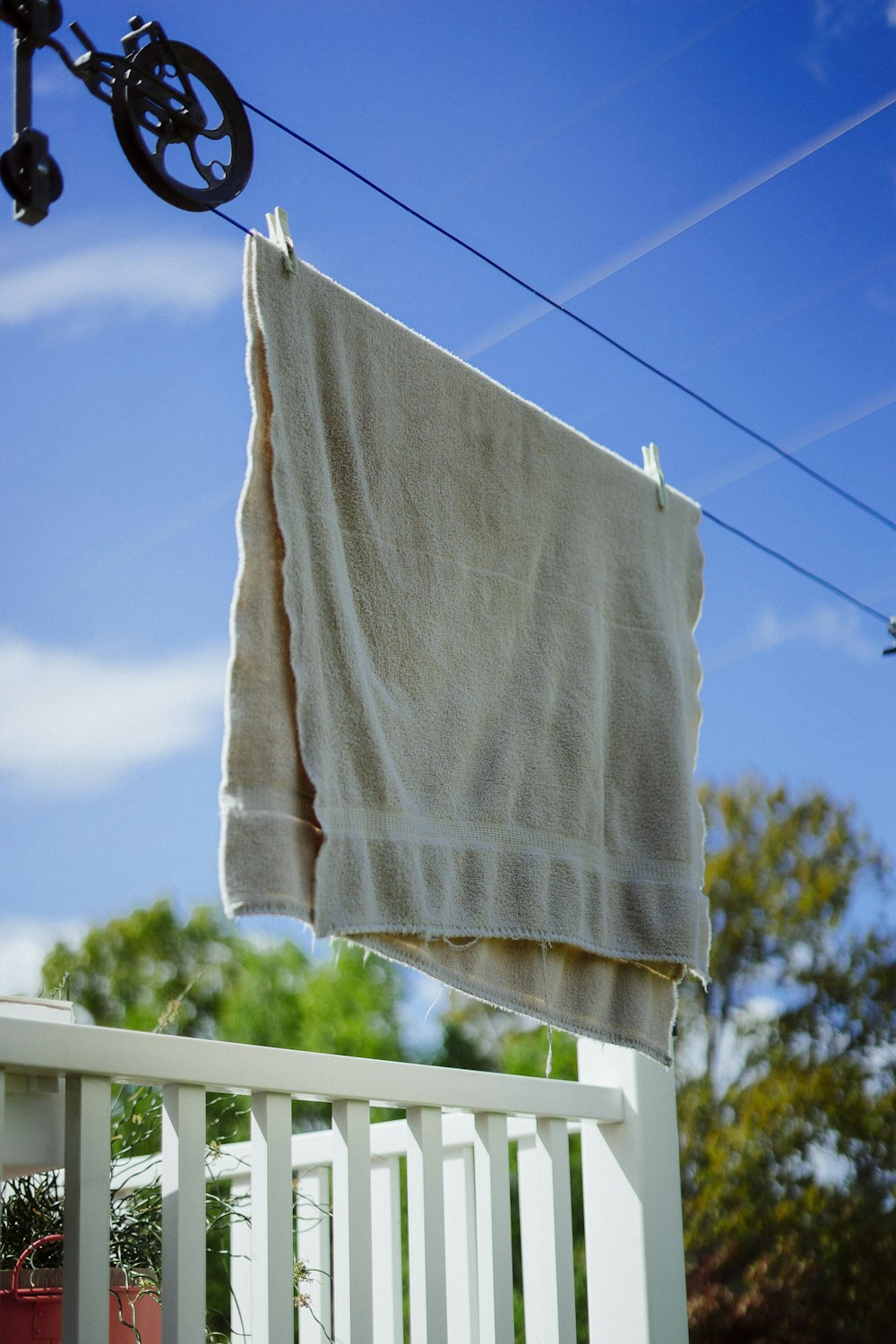 white textile on white wooden fence