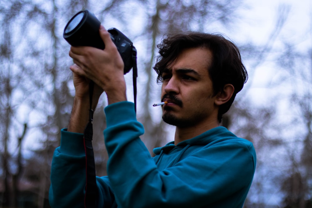 man in blue hoodie holding black camera