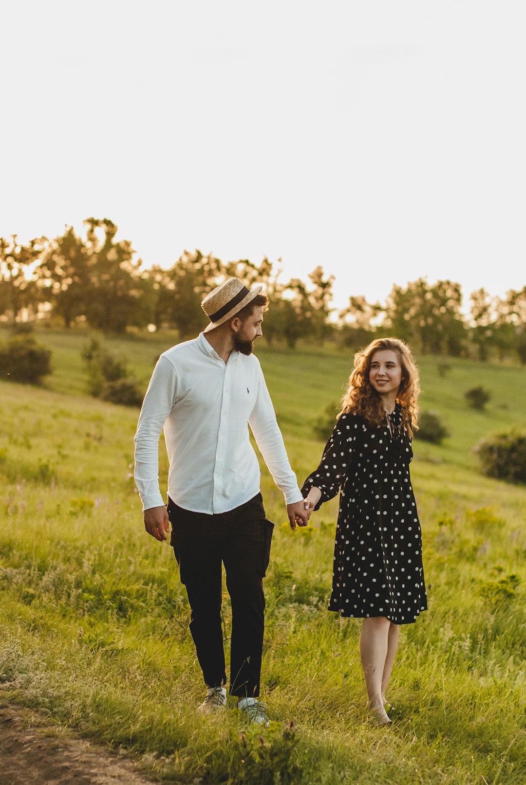 man in white dress shirt and woman in black dress standing on green grass field during