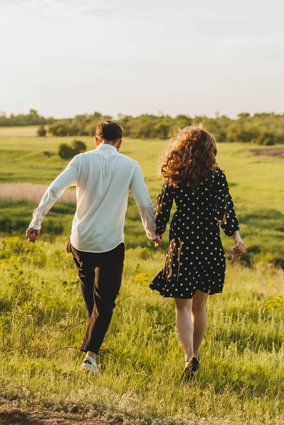 man and woman walking on green grass field during daytime