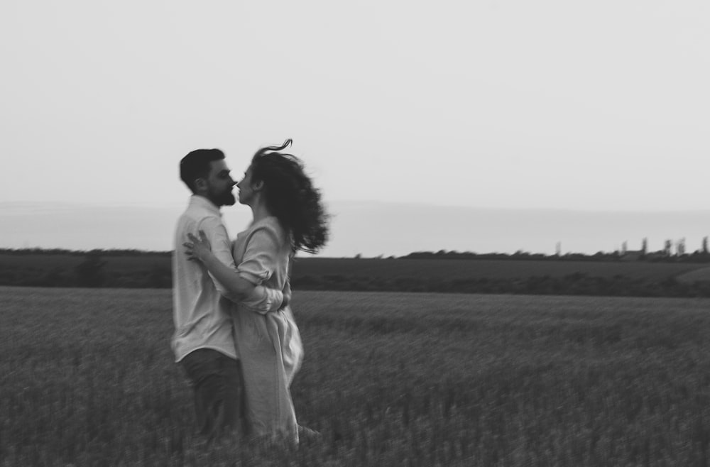 草原でキスをするカップルのグレースケール写真