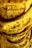 A close-up view of yellow fabric with black script text printed on it. The fabric appears to be folded or layered, creating shadows and depth. There are subtle reddish floral patterns interspersed with the text.