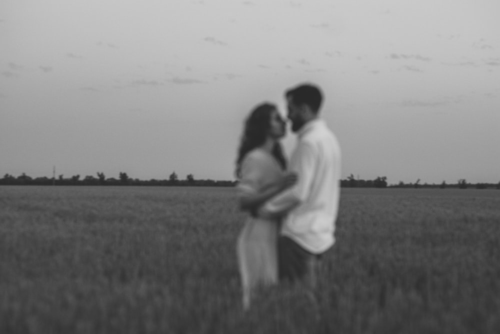 man and woman kissing on grass field during daytime