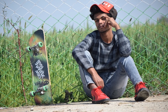 man in black and gray plaid dress shirt and red pants sitting on brown wooden log in Rajasthan India