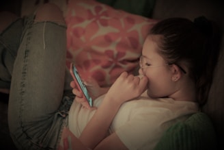 A person happily playing a mobile game on a smartphone in a cozy living room.