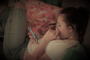 Person reading product reviews on a smartphone in a cozy setting.