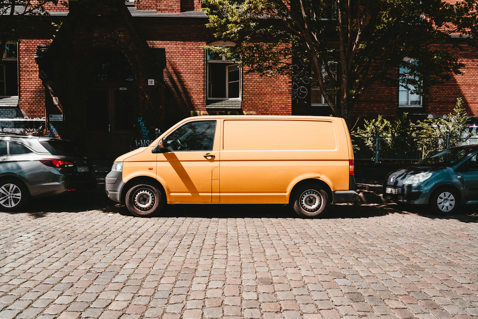 A yellow delivery van parked beside a brick building