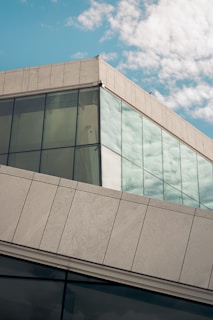 A modern building with large glass windows reflecting the sky.