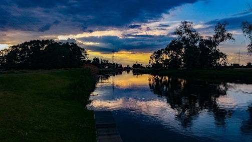 A serene landscape at sunset with rich colors and calm water reflections.