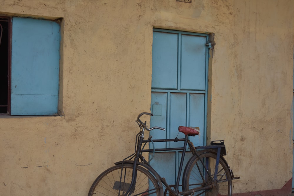 black city bike parked beside blue wooden door