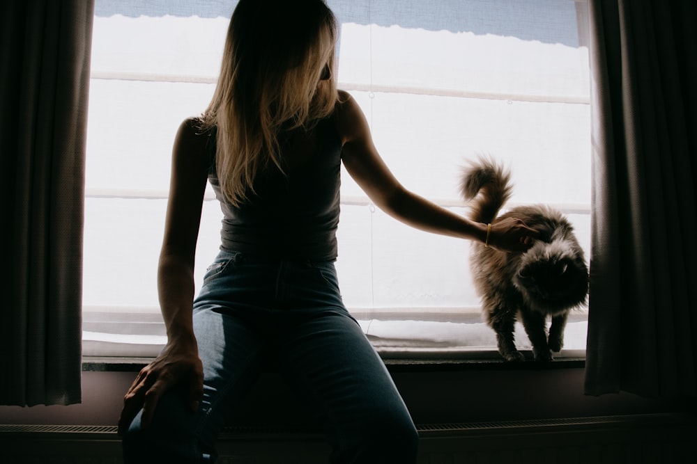 woman in black tank top and blue denim jeans sitting on window