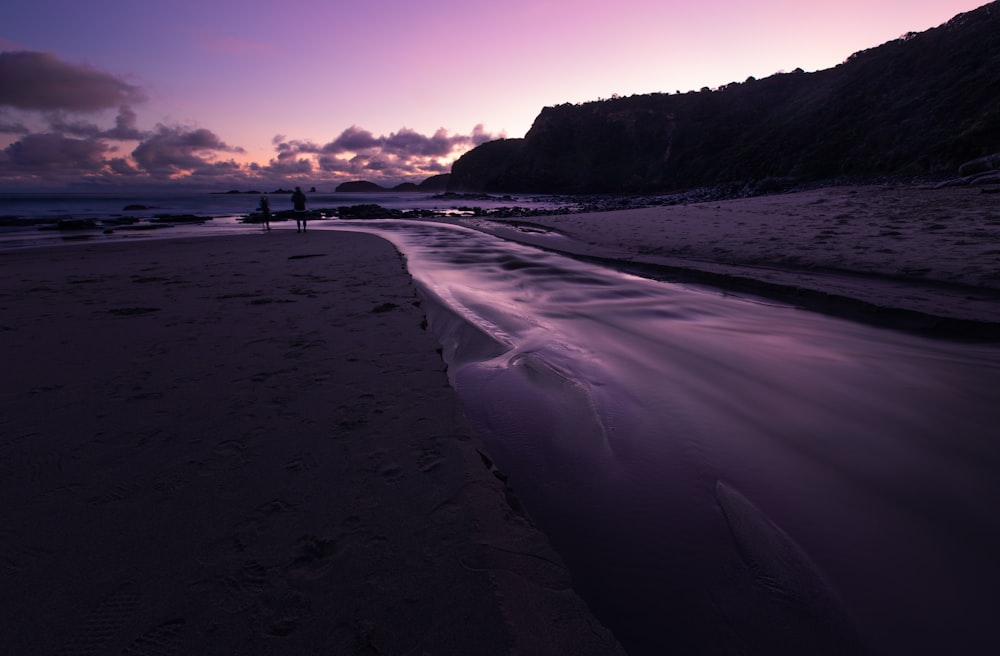 silhouette of person walking on beach during sunset