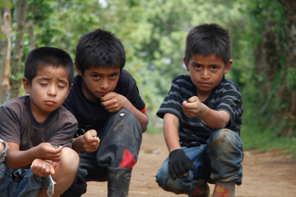 2 boys sitting on ground during daytime