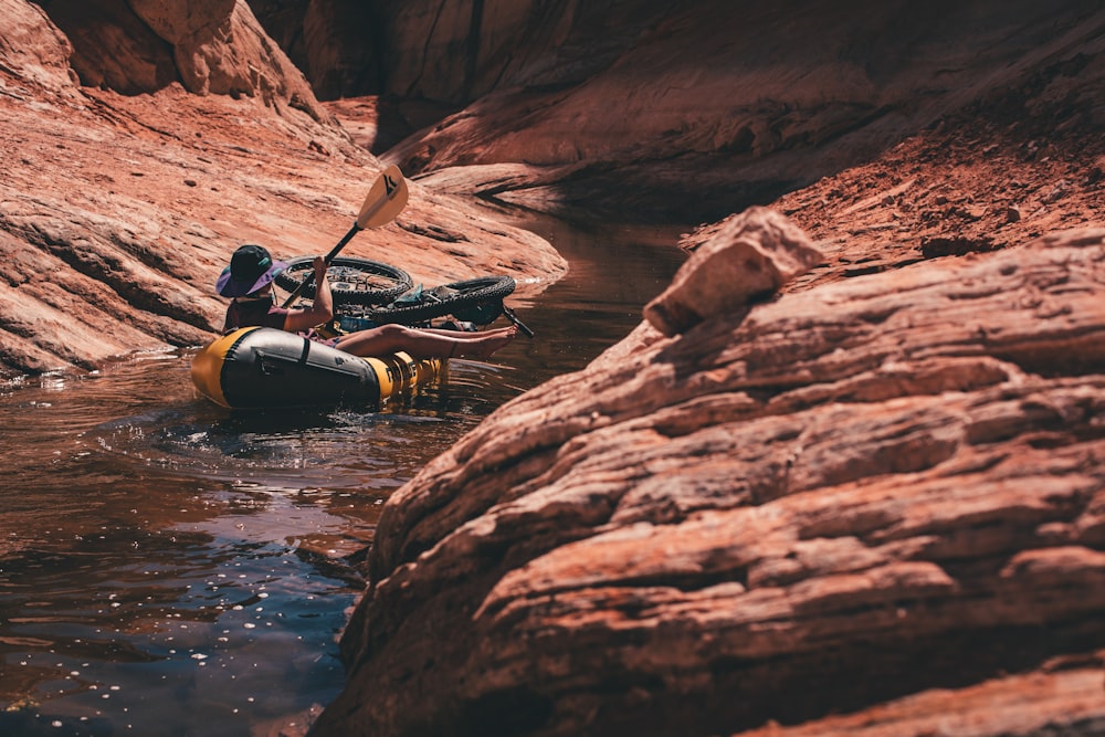 man in black jacket riding on black kayak on river during daytime