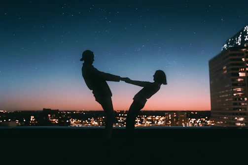 Sunset silhouette of a couple holding hands on a Mumbai rooftop.