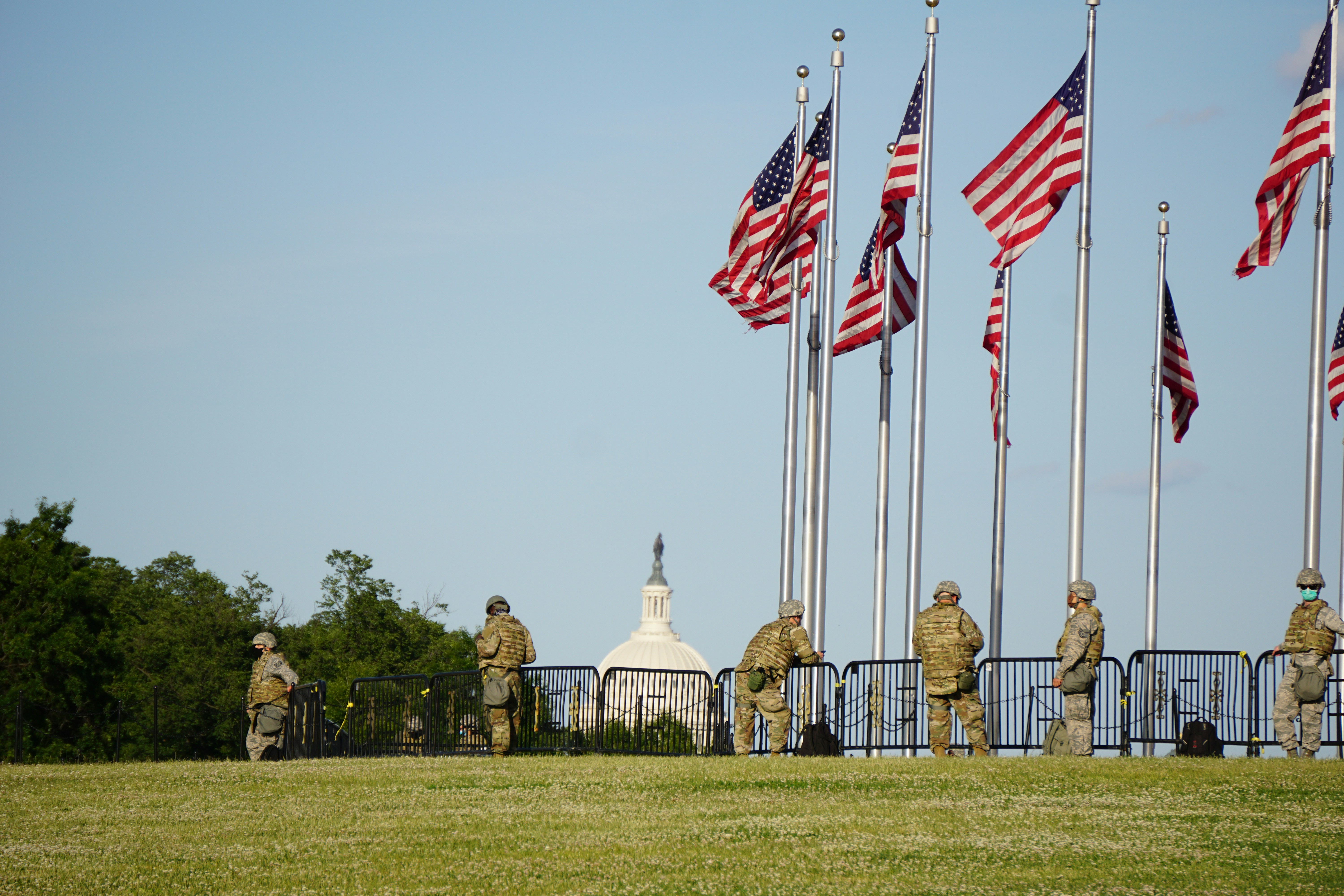 people standing on green grass field with flags during daytime washington monument teams background