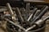 A collection of various metal tools, including taps and drill bits, are placed upright in a container. The tools have a metallic sheen and are surrounded by curly metal shavings, suggesting a workshop setting.