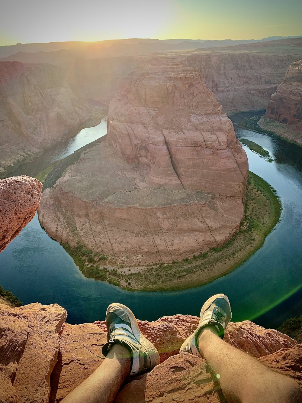 person in green pants and green sneakers sitting on brown rock formation during daytime
