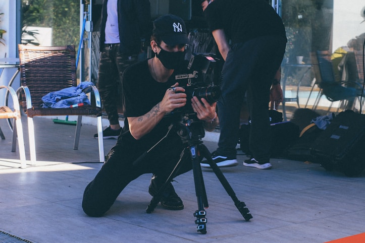 man in black t-shirt and black pants holding black dslr camera