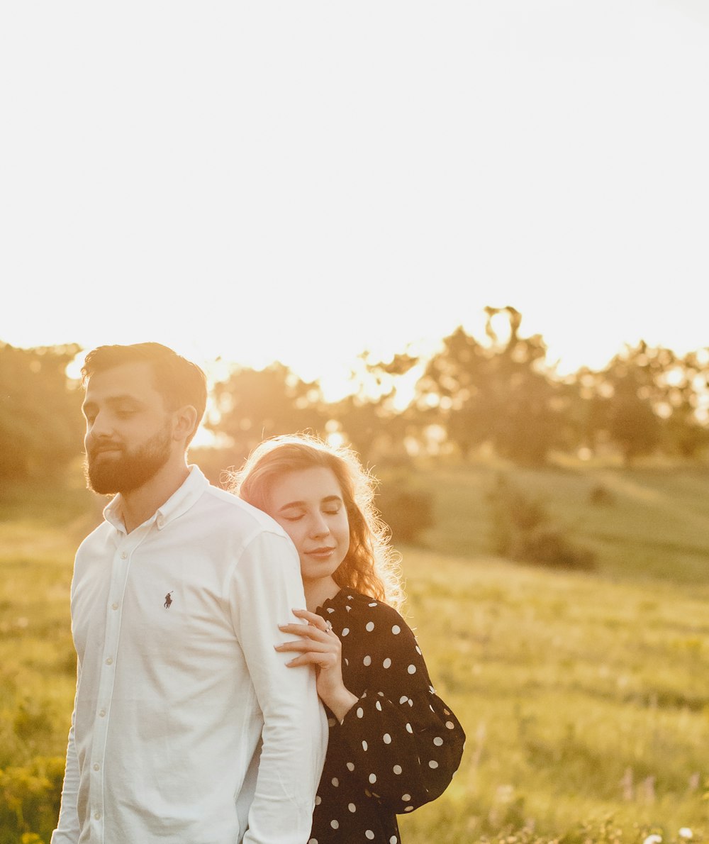 man in white dress shirt holding woman in black and white polka dot dress