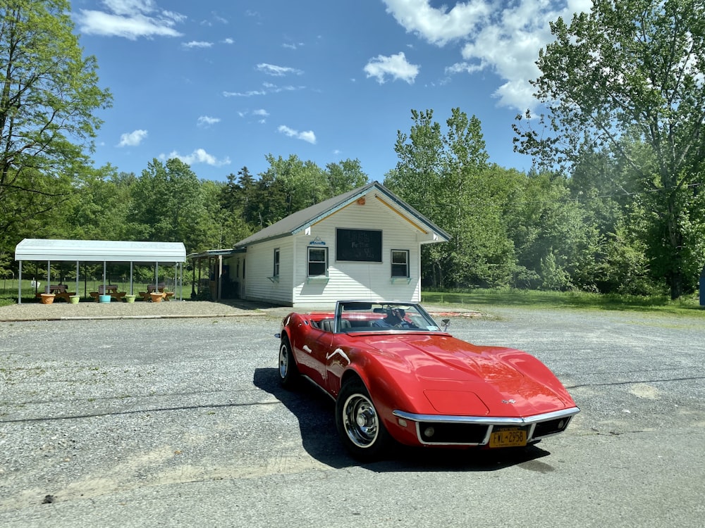 red car parked in front of white and brown house