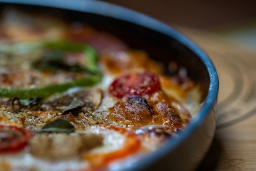 A top-down view of a freshly baked pizza with vibrant toppings, surrounded by herbs.