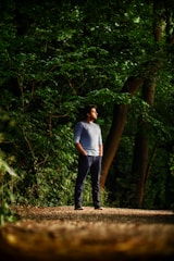A person standing at a forked path in a forest, looking thoughtfully toward multiple directions.