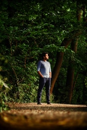 A person standing at a crossroads in a peaceful forest, looking thoughtful.
