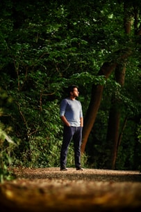 A person standing at a crossroads in a peaceful forest, looking thoughtful.