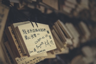 Wooden plaques with handwritten messages hang closely together. The text on the plaques is in different languages, including Chinese and English, and appears to contain personal messages or wishes.