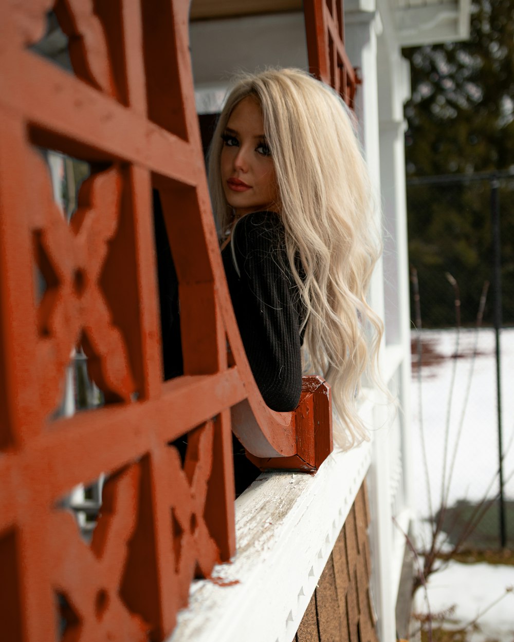 woman in black long sleeve shirt leaning on brown wooden fence during daytime