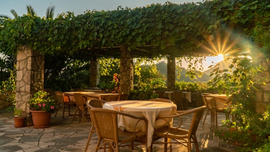 A sunlit terrace of a small villa with rustic stone walls and comfortable outdoor seating.
